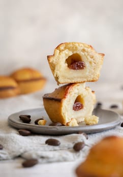 Pasticciotto leccese pastry filled with egg custard cream and sour cherry jam. Cut in half pasticiotto on a plate served for typical apulian breakfast, close up. Table decorated with coffee beans
