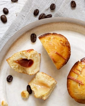 Pasticciotto leccese pastry filled with egg custard cream and sour cherry jam. Pieces of pasticiotto on a plate, typical apulian breakfast, top view. Table decorated with coffee beans