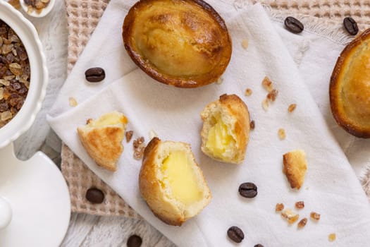 Pasticciotto leccese pastry filled with egg custard cream, typical sweet from Lecce, Italy. Pieces of pasticiotto on a beige napkin, apulian breakfast with coffee prepared, top view