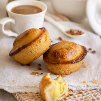 Pasticciotto leccese pastry filled with egg custard cream, typical sweet from Lecce, Italy. Pieces of pasticiotto on a beige napkin, apulian breakfast with coffee prepared, close up