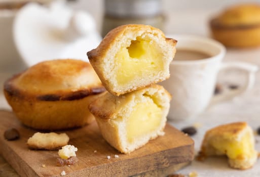 Pasticciotto leccese pastry filled with egg custard cream, typical sweet from Lecce, Italy. Pieces of pasticiotto on a wooden board, apulian breakfast with coffee prepared, close up