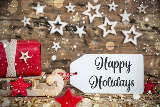 Wooden Sled With Red Gift And Rustic Snowy Christmas Background With Label With Text Happy Holidays