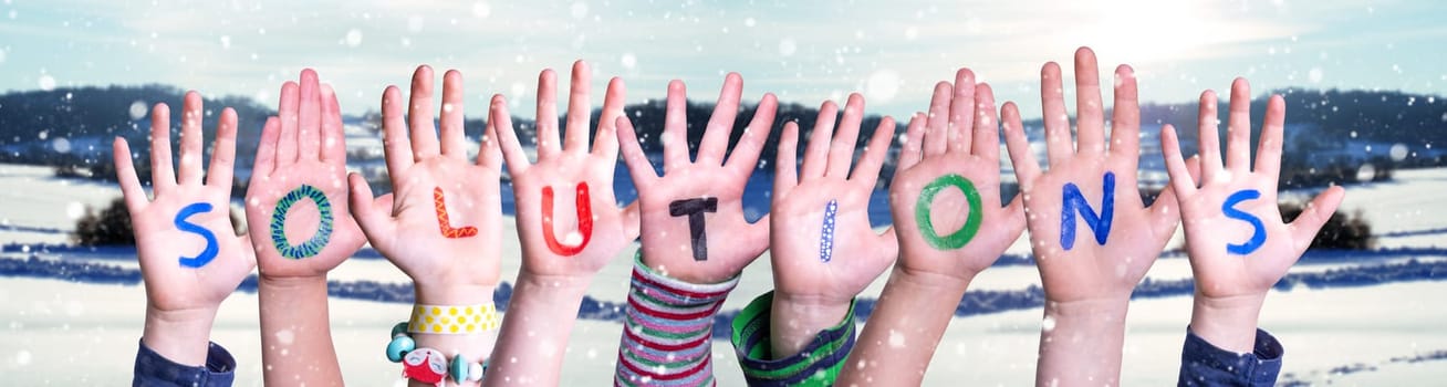 Children Hands Building Colorful English Word Solutions. White Snowy Winter Scenery And Landscape With Snowflakes As Background.