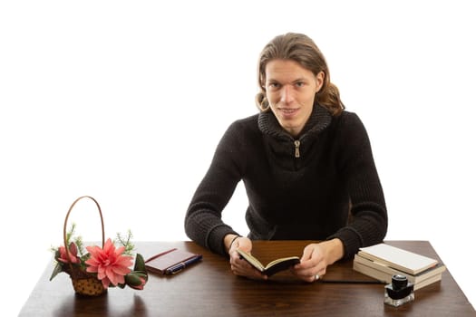 A student sits at a table and reads a book on a white background