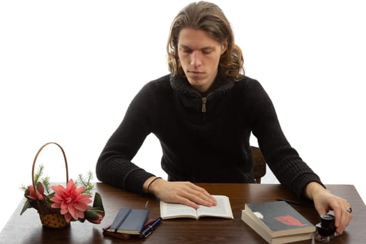 A student sits at a table and reads a book on a white background