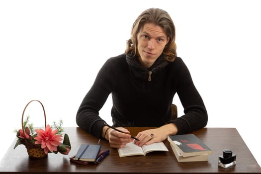 A student sits at a table and reads a book on a white background