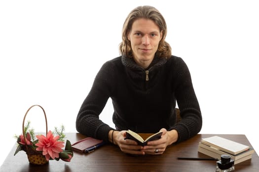 A student sits at a table and reads a book on a white background