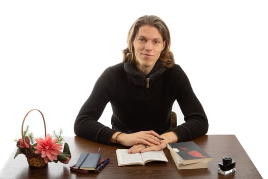 A student sits at a table and reads a book on a white background