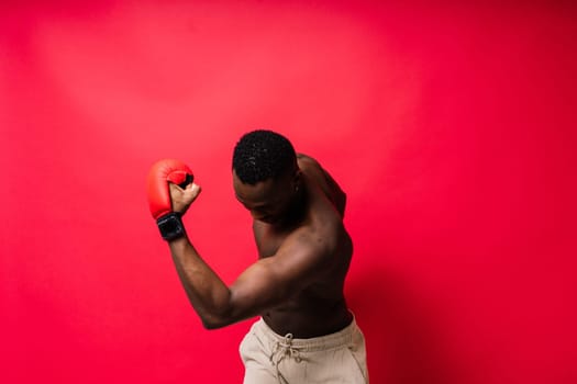 Muscular serious looking african boxer training, in studio red background