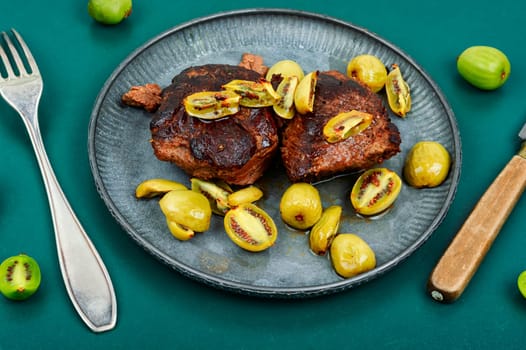 Roasted ostrich steak and mini kiwi on a plate