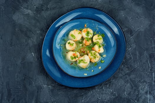 Fried scallops with green on a plate, seafood. Top view.