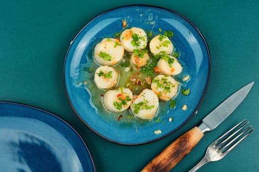 Fried scallops with green on a plate, seafood. Top view.