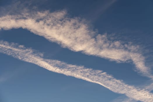 Landscape of a beautiful blue sky with clouds and white vapor trails in the evening. Nature.