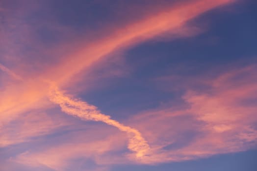 Landscape of a beautiful blue sky with clouds and white vapor trails at sunset. Nature.