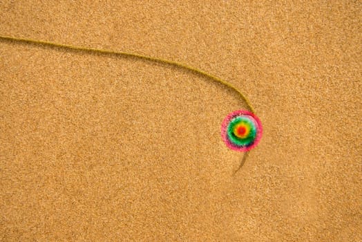 Sand of a beach with pebble and alga thread with a rainbow circle