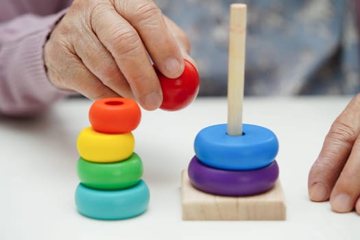 Asian elderly woman playing puzzles game to practice brain training for dementia prevention, Alzheimer disease.