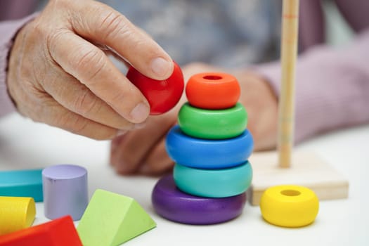 Asian elderly woman playing puzzles game to practice brain training for dementia prevention, Alzheimer disease.