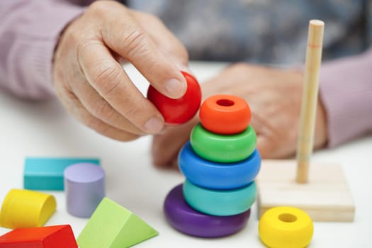 Asian elderly woman playing puzzles game to practice brain training for dementia prevention, Alzheimer disease.