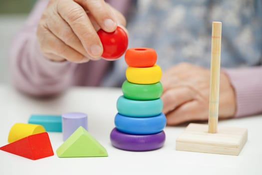 Asian elderly woman playing puzzles game to practice brain training for dementia prevention, Alzheimer disease.