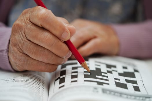 Asian elderly woman playing sudoku puzzle game to practice brain training for dementia prevention, Alzheimer disease.