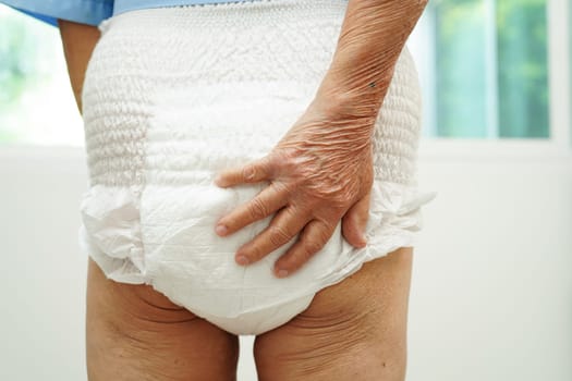 Asian senior woman patient wearing adult incontinence diaper pad in hospital.