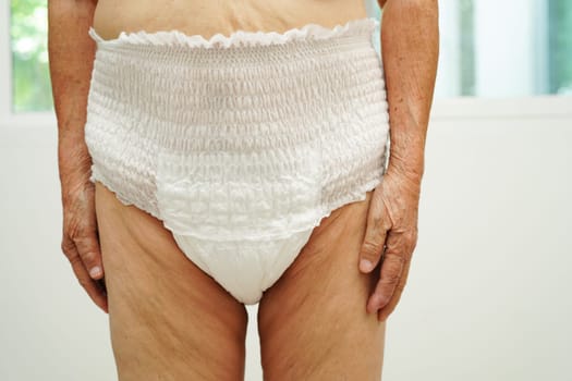 Asian senior woman patient wearing adult incontinence diaper pad in hospital.