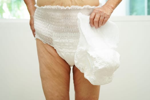 Asian senior woman patient wearing adult incontinence diaper pad in hospital.