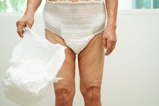Asian senior woman patient wearing adult incontinence diaper pad in hospital.
