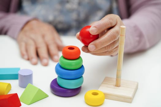 Asian elderly woman playing puzzles game to practice brain training for dementia prevention, Alzheimer disease.