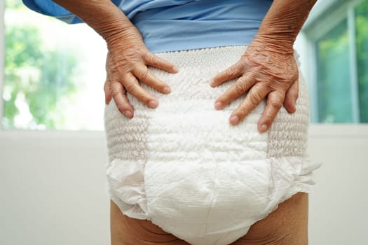Asian senior woman patient wearing adult incontinence diaper pad in hospital.
