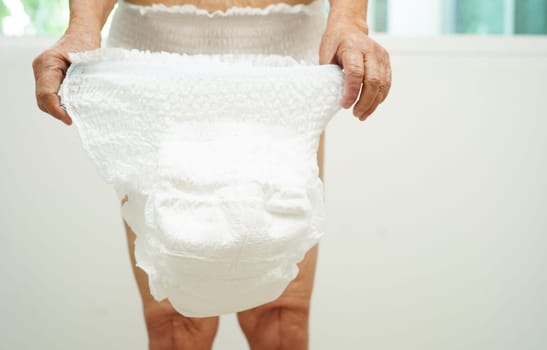 Asian senior woman patient wearing adult incontinence diaper pad in hospital.