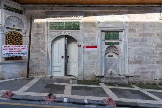 Side entrance and drinking fountain attached to Ahmediye Mosque in Uskudar, Istanbul, Turkey. The fountain is made of white marble and has a green plaque on it, written in Arabic