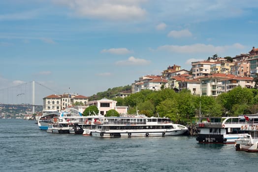 Istanbul, Turkey - May 8, 2023: Modern passenger ferry boats docked at Uskudar terminal, with Bosphorus bridge in the background