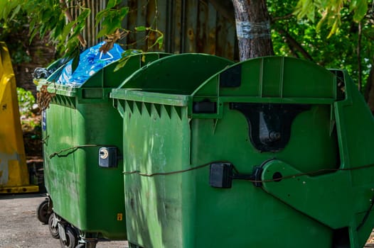 Green plastic bins for garbage waste on the street. Trash can. A place for collecting human waste. Pollution of city streets. Ecology in the city. Public place.