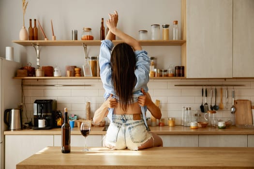 Passionate man undressing beloved woman. Loving couple erotic games on home kitchen. Romantic people relations