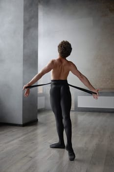 Athletic man dancer performing at studio view from back. Contemporary art ballet style