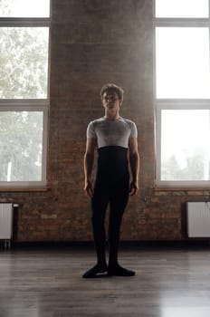Full-length portrait of handsome athletic ballet dancer in studio room. Training class for creative occupation