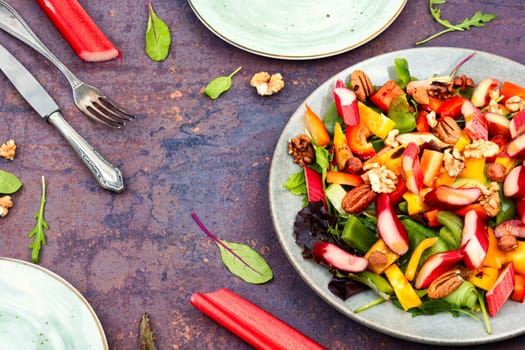 Tasty salad bowl with pepper, rhubarb, nuts and lettuce.