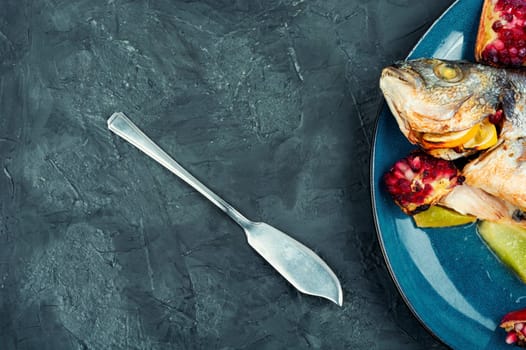 Tasty baked dorado fish with melon and pomegranate. Space for text.