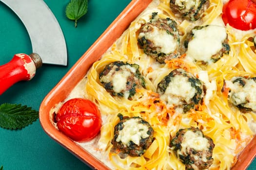 Meatballs served over appetizing noodles in baking dish. Italian food.