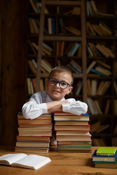 Back to school concept. Happy little schoolboy leaning on stack on textbooks ready to study hard on remote lessons of virtual classroom platform