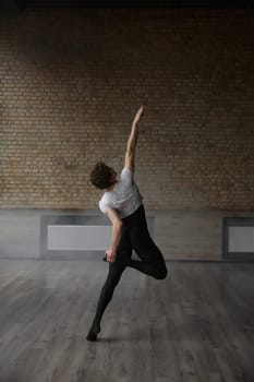 Contemporary ballet male dancer posing for camera performing body stretching routine. Modern dancing studio