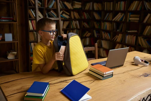 Little boy student preparing for elementary school online education process from home. Pupil sitting at desk getting ready for remote lesson