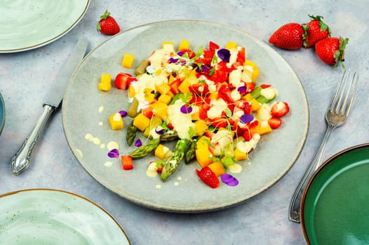 Yummy healthy salad with spice, strawberries, yogurt and mango on the plate.