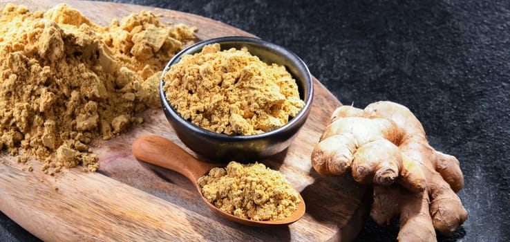 A bowl with ground ginger and its fresh rhizome.