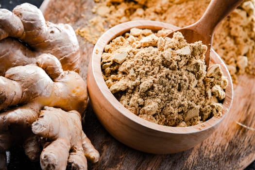 A bowl with ground ginger and its fresh rhizome.