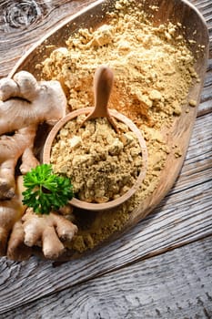 A bowl with ground ginger and its fresh rhizome.
