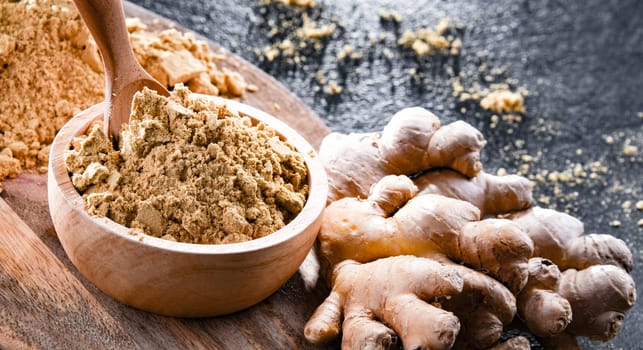 A bowl with ground ginger and its fresh rhizome.