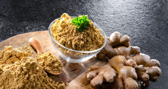 A bowl with ground ginger and its fresh rhizome.