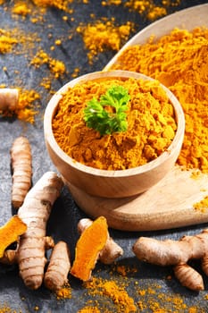 Composition with a bowl of ground turmeric and its fresh rhizome.